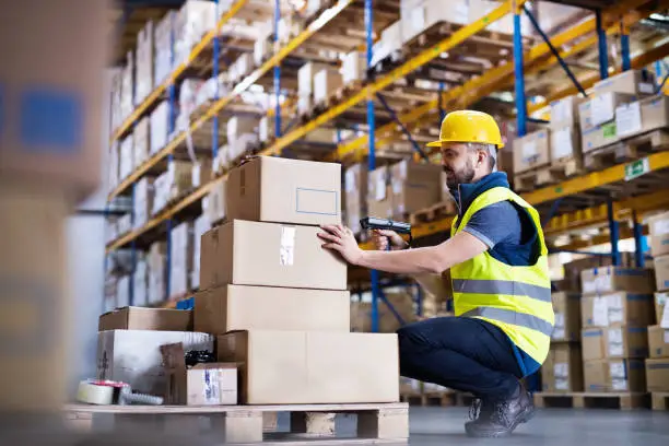 Young male warehouse worker with barcode scanner.