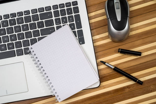 istock business concept - laptop, blank notepad, pen and mouse 892835050