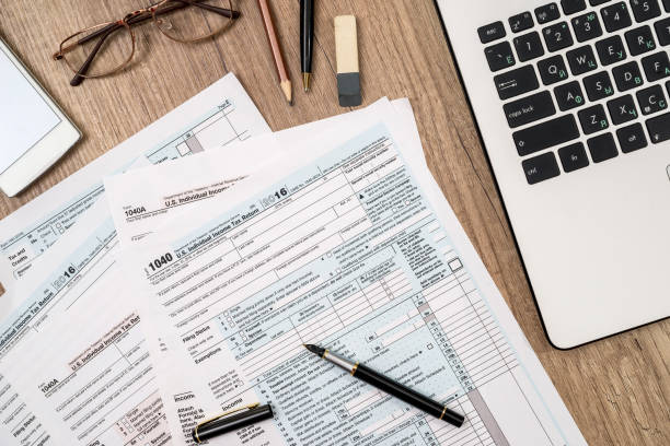 istock tax form, laptop, coffee and dollar on desk 892840476