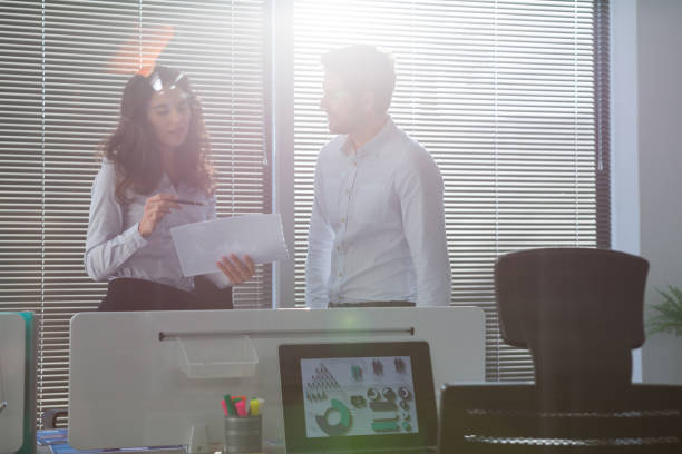 istock Male and female executives discussing over document 892847408