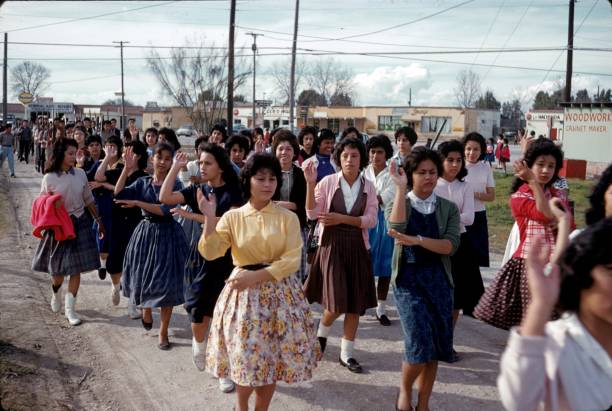 College students in Texas, 1960 Texas, USA, 1960. A group of college students moving in a city (unfortunately unknown) in Texas. In the foreground, the Mexican-born young women dance a traditional Spanish dance. In the background the young men march after the women with rifles in their hands and in military order. human rights photos stock pictures, royalty-free photos & images