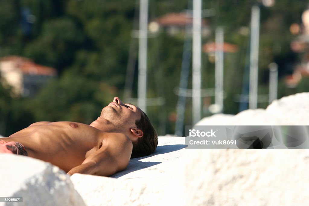 Muscolare uomo è disteso sulla spiaggia - Foto stock royalty-free di Modello dimostrativo