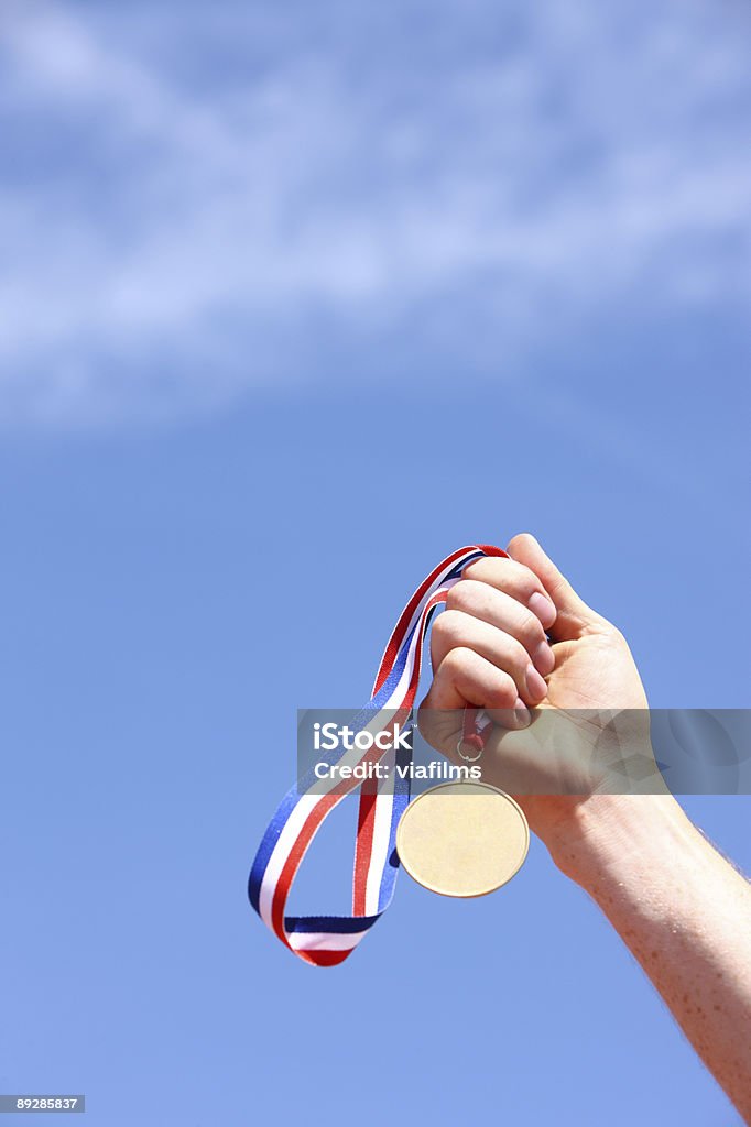 Hand, die Goldmedaille gegen blauen Himmel - Lizenzfrei Anreiz Stock-Foto