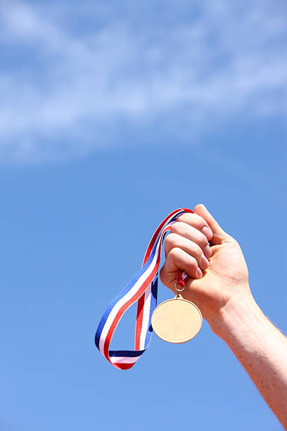 istock Hand holding gold medal against blue sky 89285837