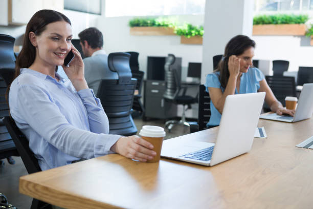 istock Female executive talking on phone while holding coffee mug 892870400