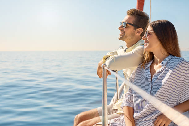 Sailing their way through summer Shot of a young couple enjoying a cruise out on the ocean barcelona province stock pictures, royalty-free photos & images