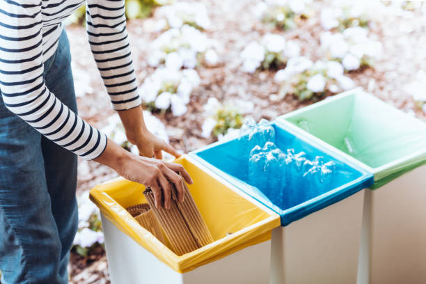 Person disposing paper to bin Person disposing paper to yellow bin on terrace with green container with glass and blue with plastic recycling bin photos stock pictures, royalty-free photos & images
