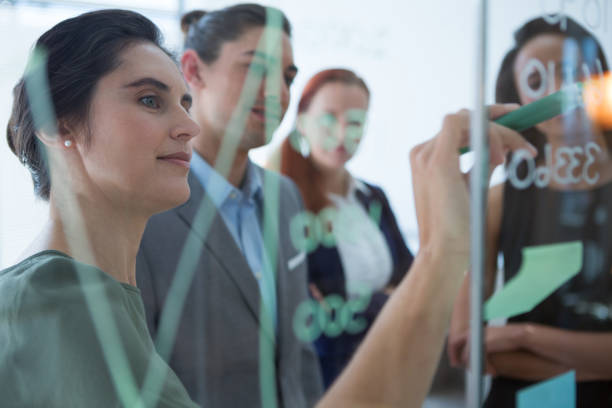 istock Group of executives discussing over information on the wall 892882892