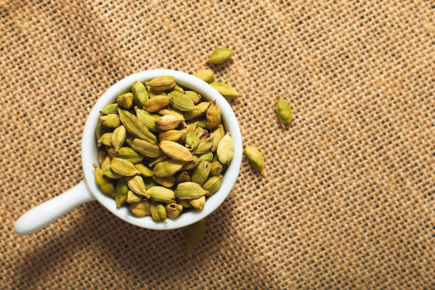 conceito de comida temperos cardamomo em copos de cerâmicos brancos de saco marrom - brown close up condiment coriander seed - fotografias e filmes do acervo