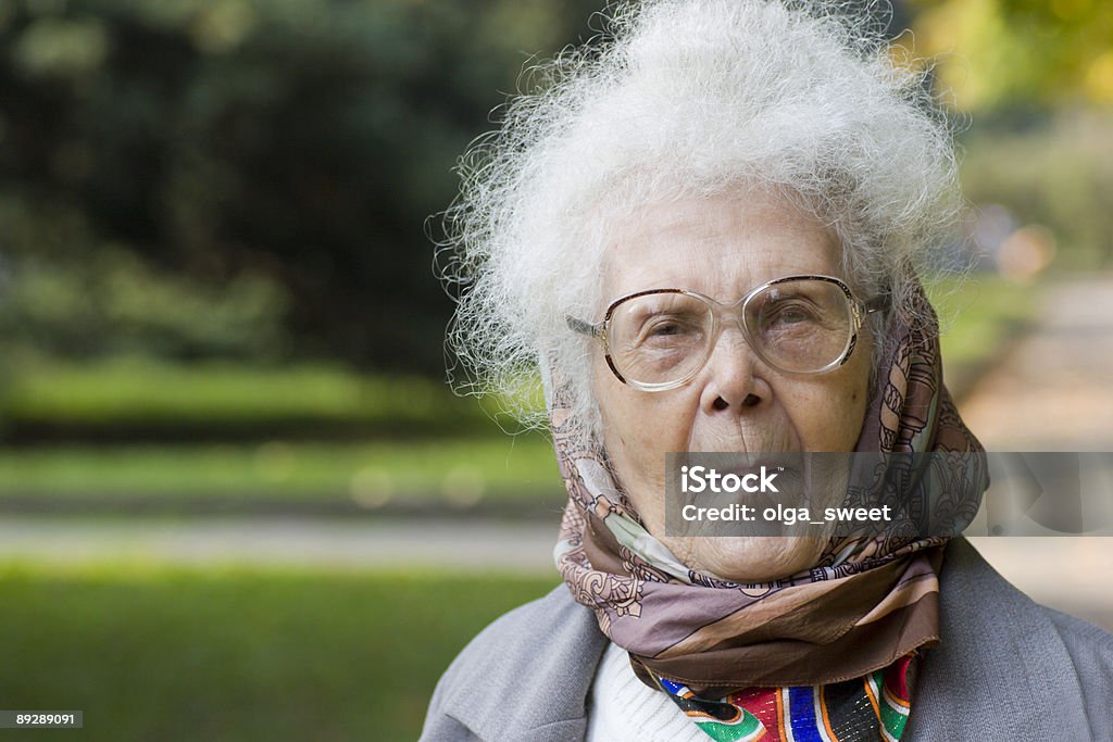 Ritratto di anziana signora nel parco - Foto stock royalty-free di Contrariato