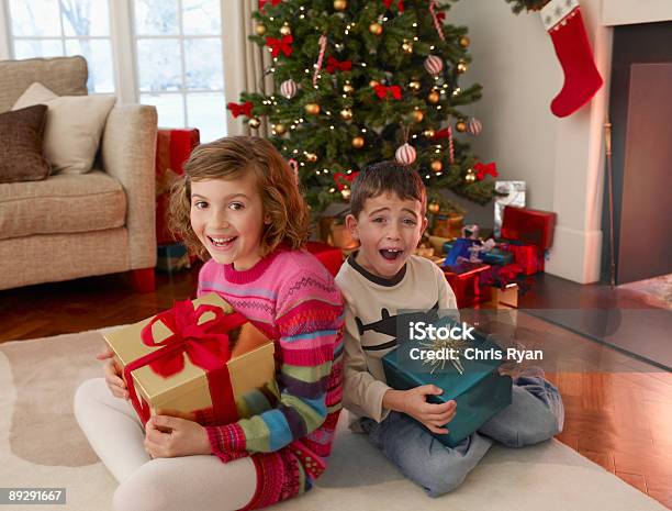 Menino E Menina Segurando Natal Presentes Na Sala De Estar - Fotografias de stock e mais imagens de 10-11 Anos