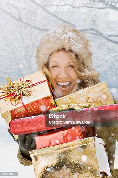 Snow Falling On Lachen Frau Holding Weihnachtsgeschenke Stockfoto und mehr Bilder von Geschenk