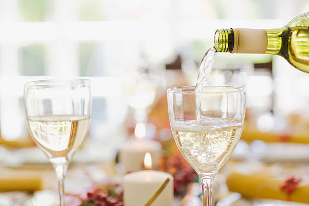 vino blanco siendo vertido en un vaso sobre una mesa - wine pouring wineglass white wine fotograf�ías e imágenes de stock