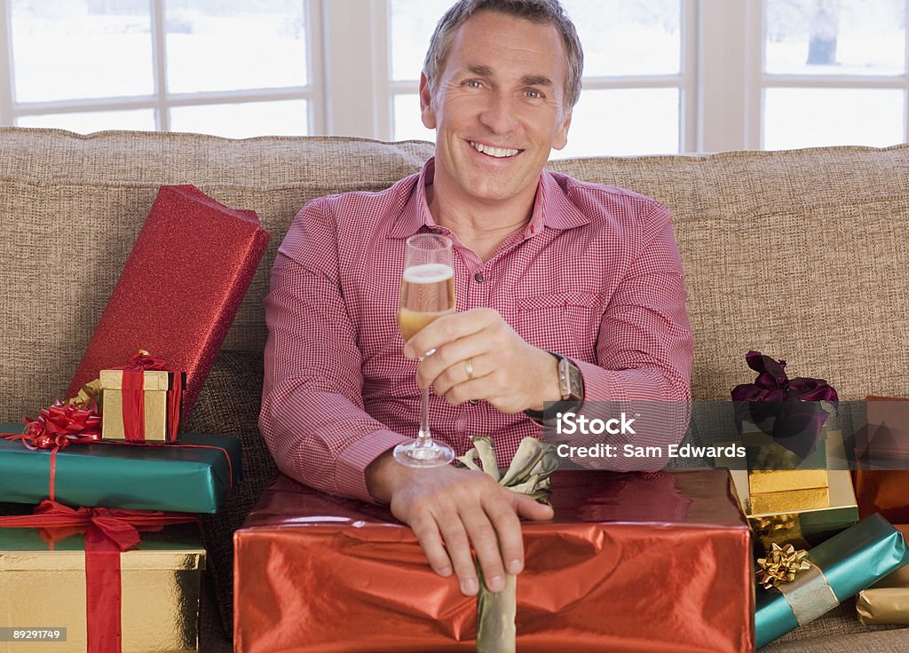 Hombre con champán rodeado de Navidad regalos - Foto de stock de Hombres libre de derechos