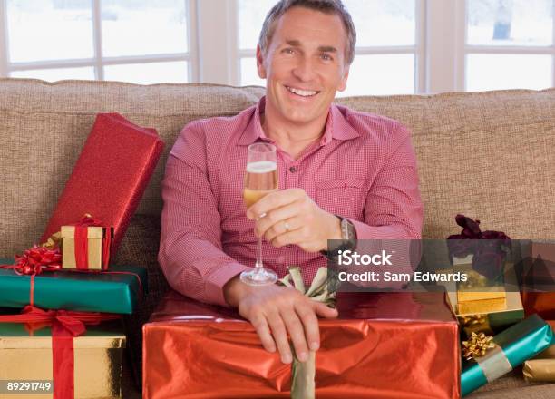 Hombre Con Champán Rodeado De Navidad Regalos Foto de stock y más banco de imágenes de Hombres - Hombres, Regalo de navidad, 45-49 años