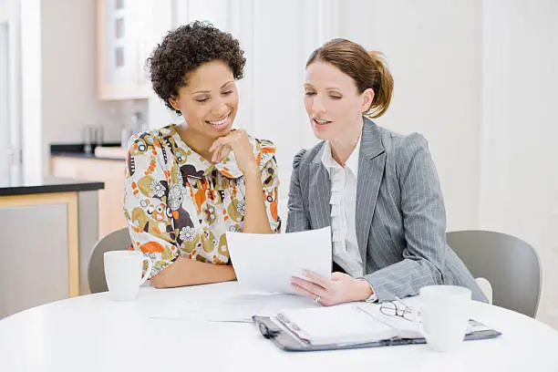 Photo of Businesswoman reviewing paperwork with woman