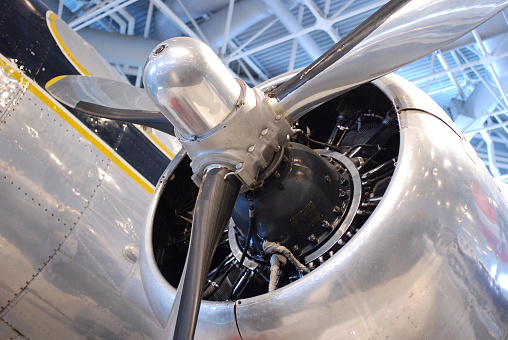 A close up shot of a large aluminum, 3 bladed propeller and engine assembly, on an aircraft.