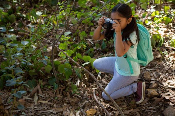 istock Little girl with backpack taking photo with camera on a sunny day 892944392