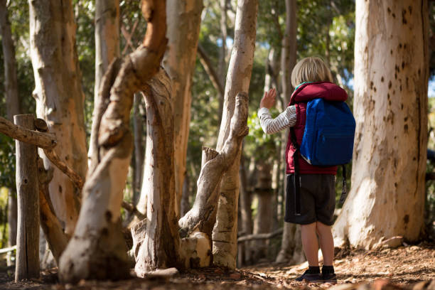 istock Little girl with backpack standing and waving her hand 892955724