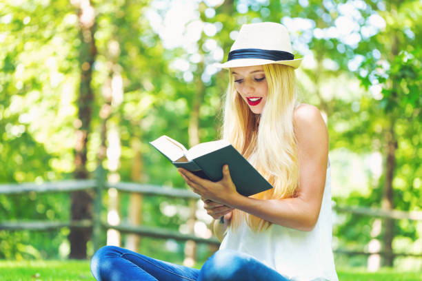 istock Young woman reading a book outside 892963166