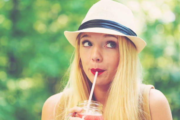 istock Young woman drinking a smoothie outside 892963188