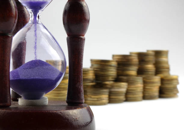 istock Hourglass and coins isolated on white background 892967788