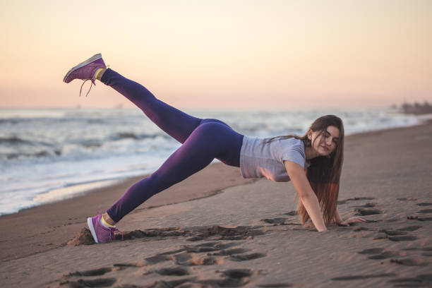Beautiful young woman doing exercise on the sandy beach, healthy relaxation