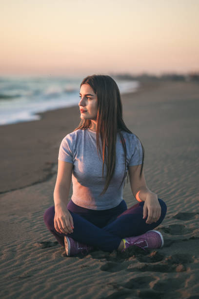 istock Beautiful young woman doing exercise on the sandy beach, healthy relaxation. 892974110
