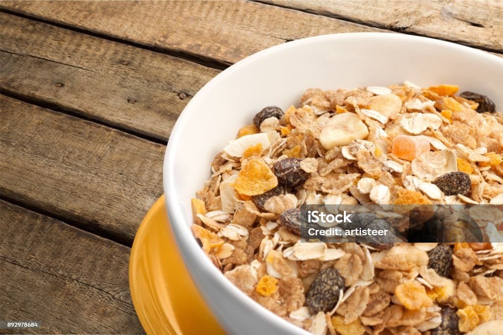 Cereal. Muesli with dried fruits in bowl. Isolated on wooden background Banana Stock Photo