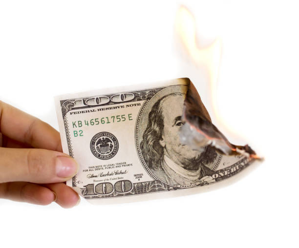 istock a hundred dollars burn in a fire on a white background 892995982