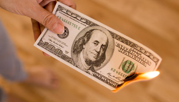istock one hundred dollars burn in flames in hand 892998142