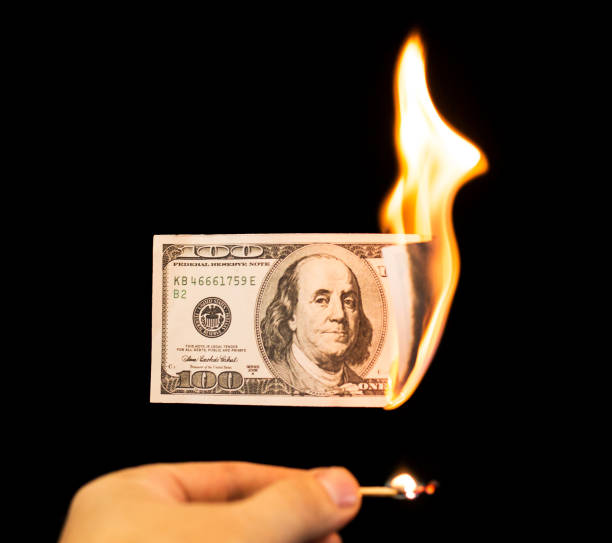 istock a hundred dollars burn in a fire on a black background 892998434
