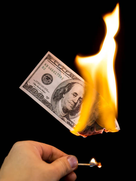 istock a hundred dollars burn in a fire on a black background 892998640