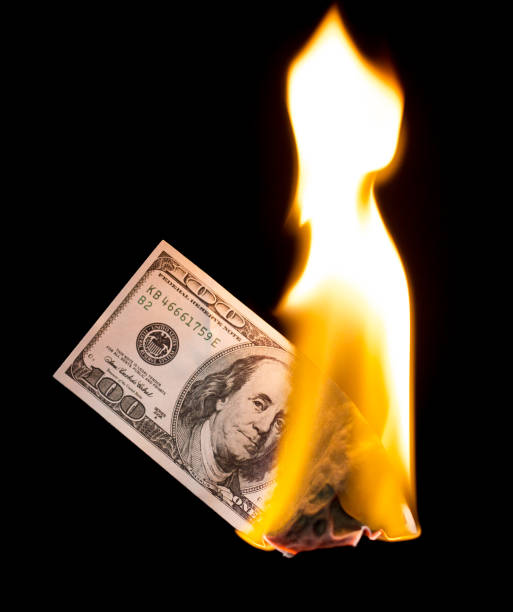 istock a hundred dollars burn in a fire on a black background 892998704
