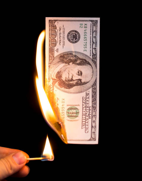 istock a hundred dollars burn in a fire on a black background 892998760