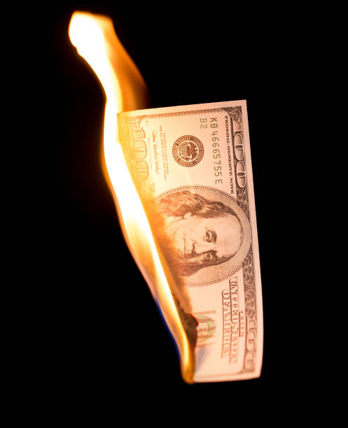 istock a hundred dollars burn in a fire on a black background 892998864