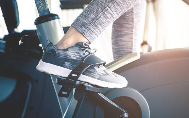 Woman feet is cycling on fitness exercising bike machine stock photo