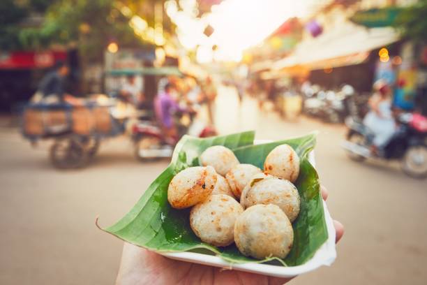 Sweet food on the street market Hand of man holding bowl with sweet coconut food. Busy street full of restaurants, bars and shops - Siem Reap, Cambodia siem reap stock pictures, royalty-free photos & images