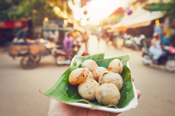 Sweet food on the street market Hand of man holding bowl with sweet coconut food. Busy street full of restaurants, bars and shops - Siem Reap, Cambodia cambodia food stock pictures, royalty-free photos & images