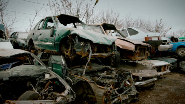close up shot of the broken cars that are on the landfill of vehicles, rusted and broken cars are waiting for the recycling