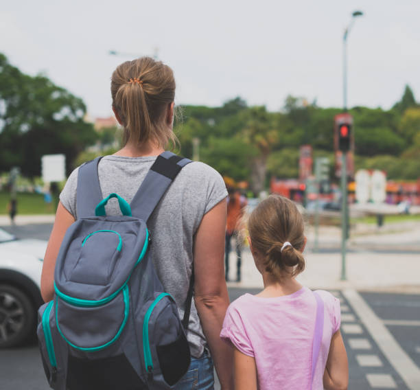 istock Mother and daughter crossing the road. Back view. 893049262