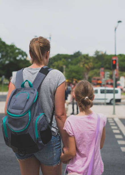 istock Mother and daughter crossing the road. Back view. 893049266