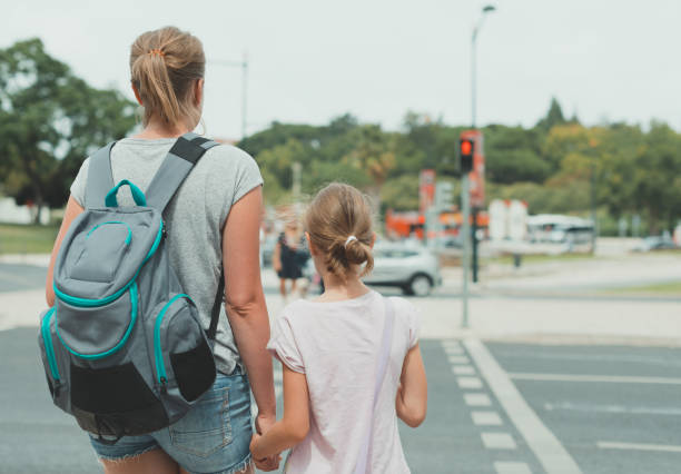 istock Mother and daughter crossing the road. Back view. 893049268