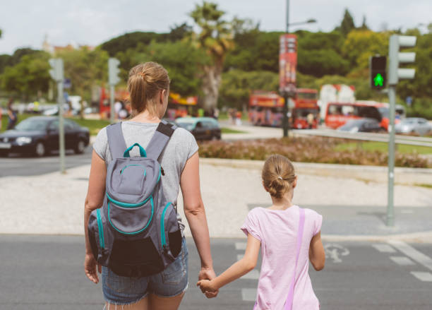 istock Mother and daughter crossing the road. Back view. 893049270