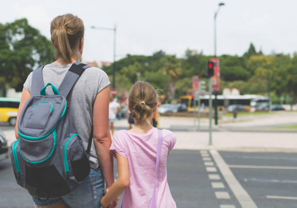 istock Mother and daughter crossing the road. Back view. 893049280