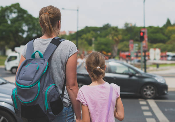 istock Mother and daughter crossing the road. Back view. 893049282