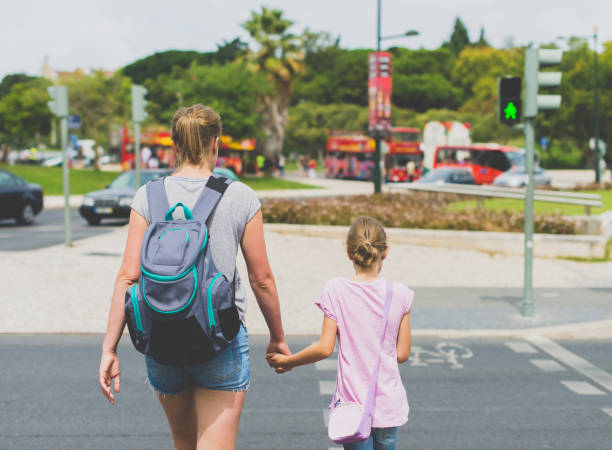 istock Mother and daughter crossing the road. Back view. 893049338