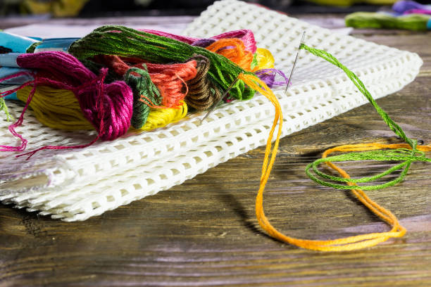 filo interdentale di diversi colori sdraiato su una grande tela lo incastrato con aghi. tavolo rustico in legno - embroidery cross stitch needle sewing foto e immagini stock