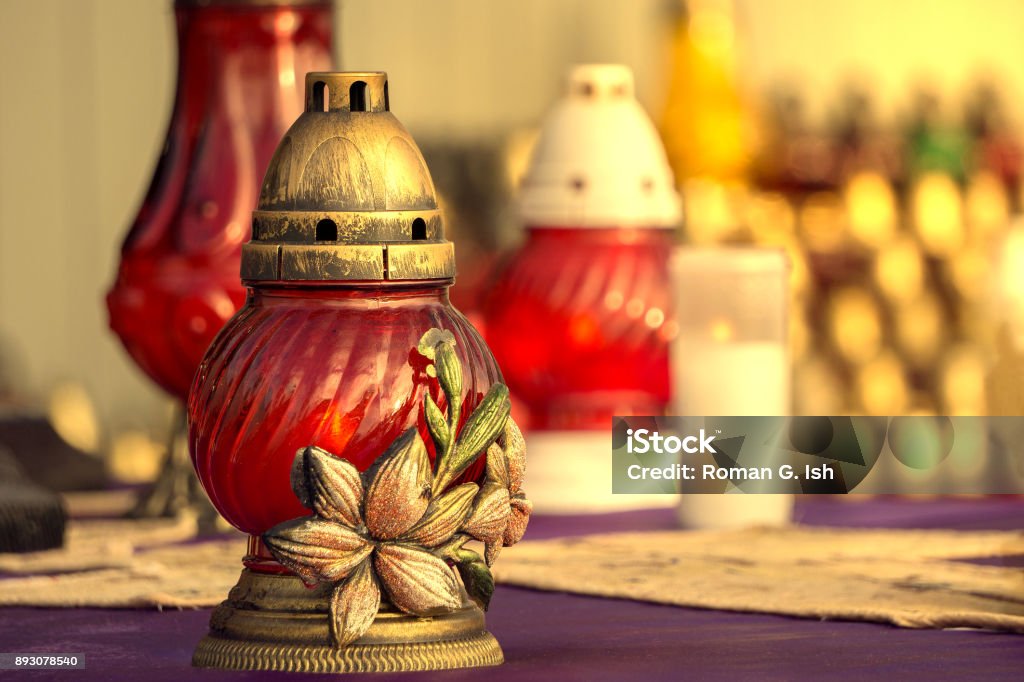 Colorful, vivid red catholic lighting candles in lanterns decorated with beautiful ornament. All Saints' Day holiday. Beauty Stock Photo