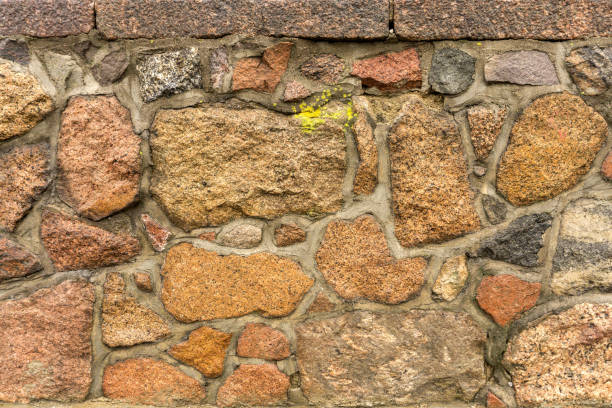 Fragment of boulder retaining wall made of natural granite stones. Texture of aged stone wall. Background stock photo
